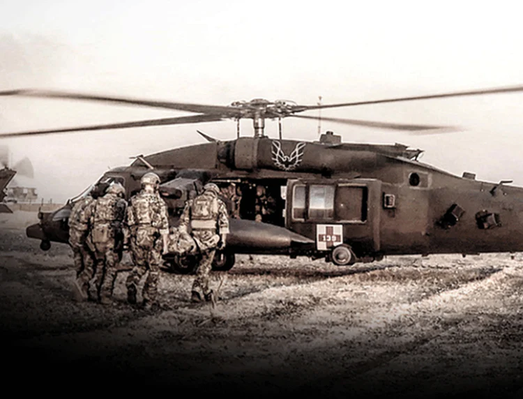 Soldiers walking toward a military helicopter on a dusty landing zone.