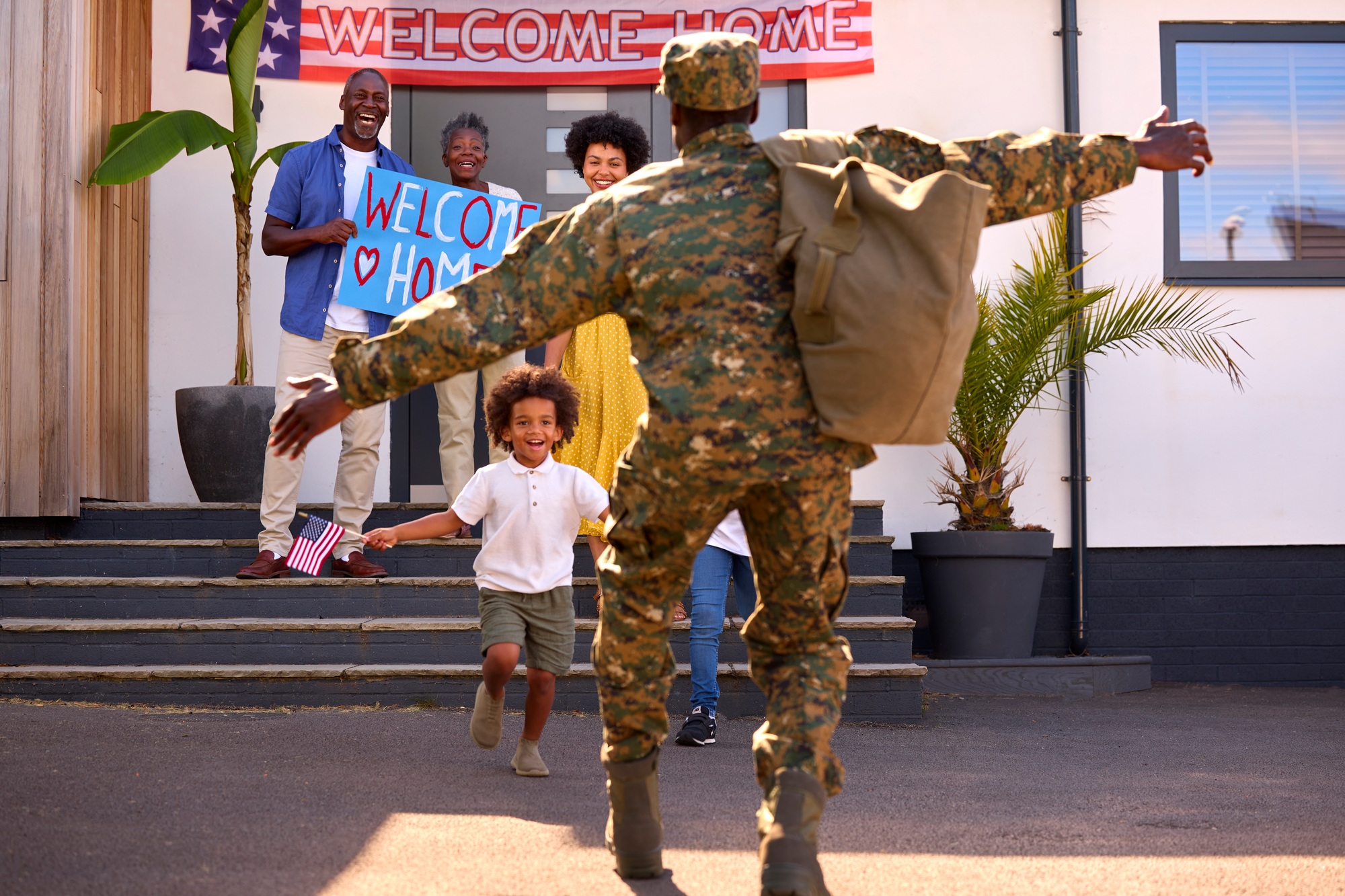 Multi-Generation Family Welcoming Army Father Home On Leave With Banner