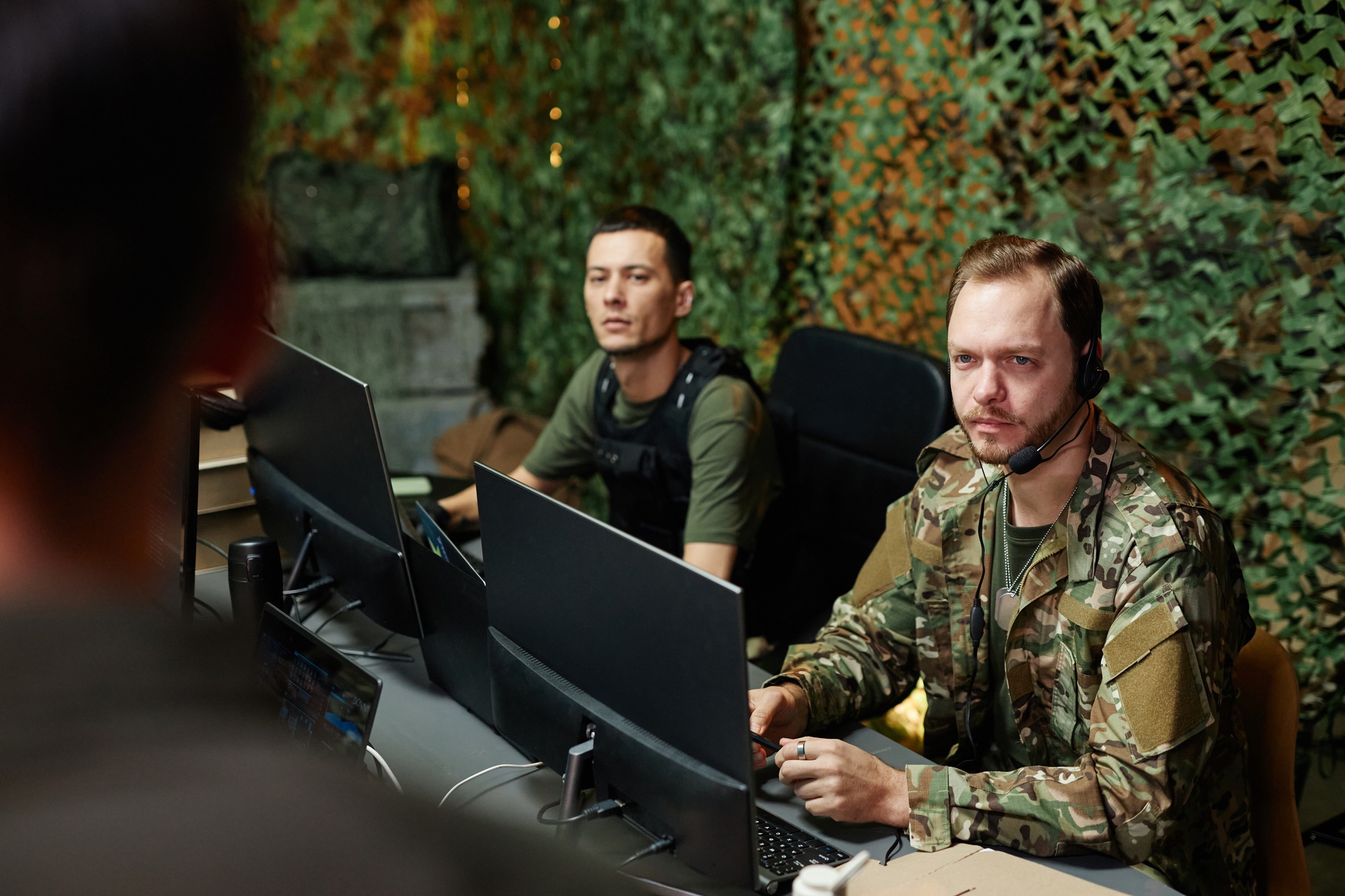 Young serious male operator of surveillance office looking at speaker