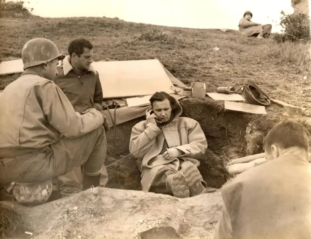 WWII soldiers communicating from a field trench with radio equipment.